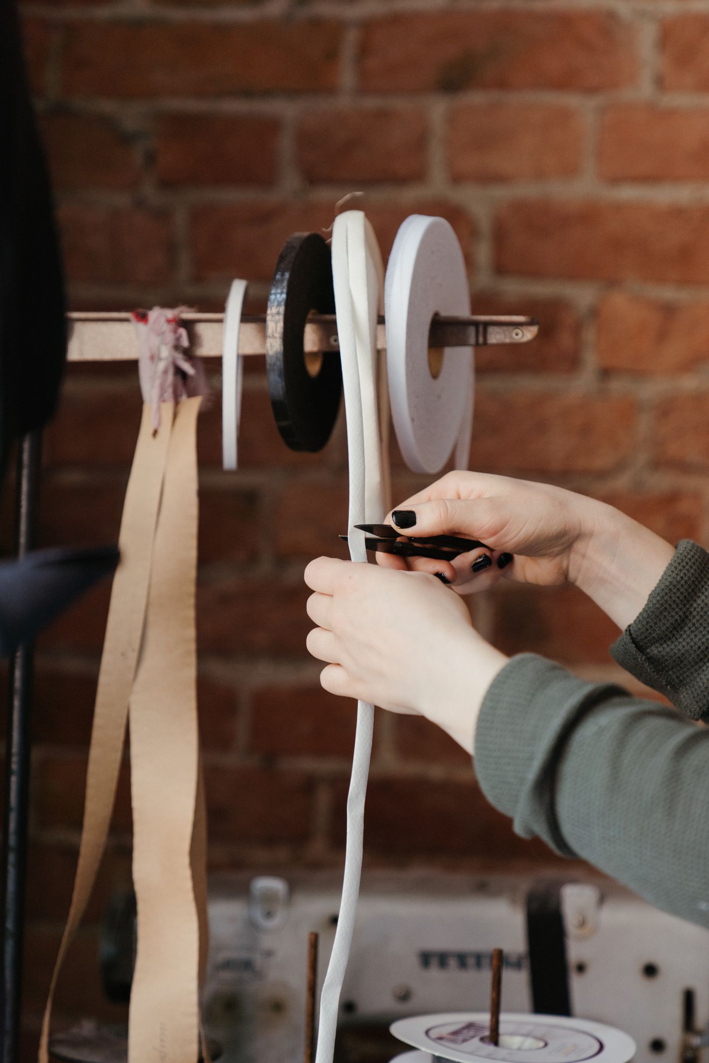 A maker's hands working with ribbon and spools