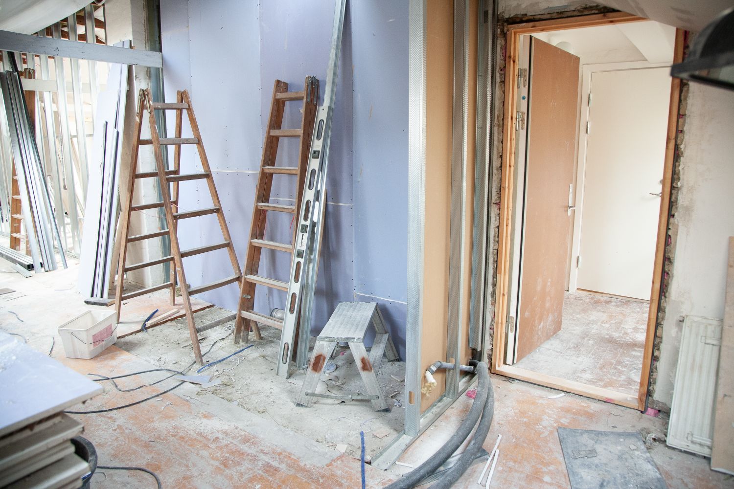 A drywall jobsite with board, metal studs and a ladder set up
