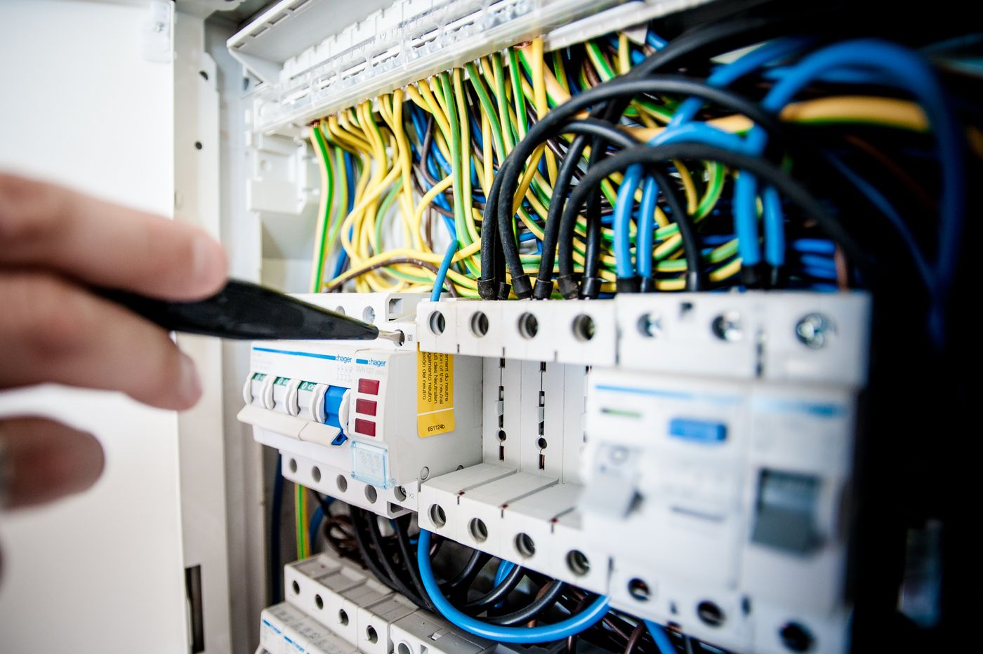 A hand at an open breaker panel during a service call
