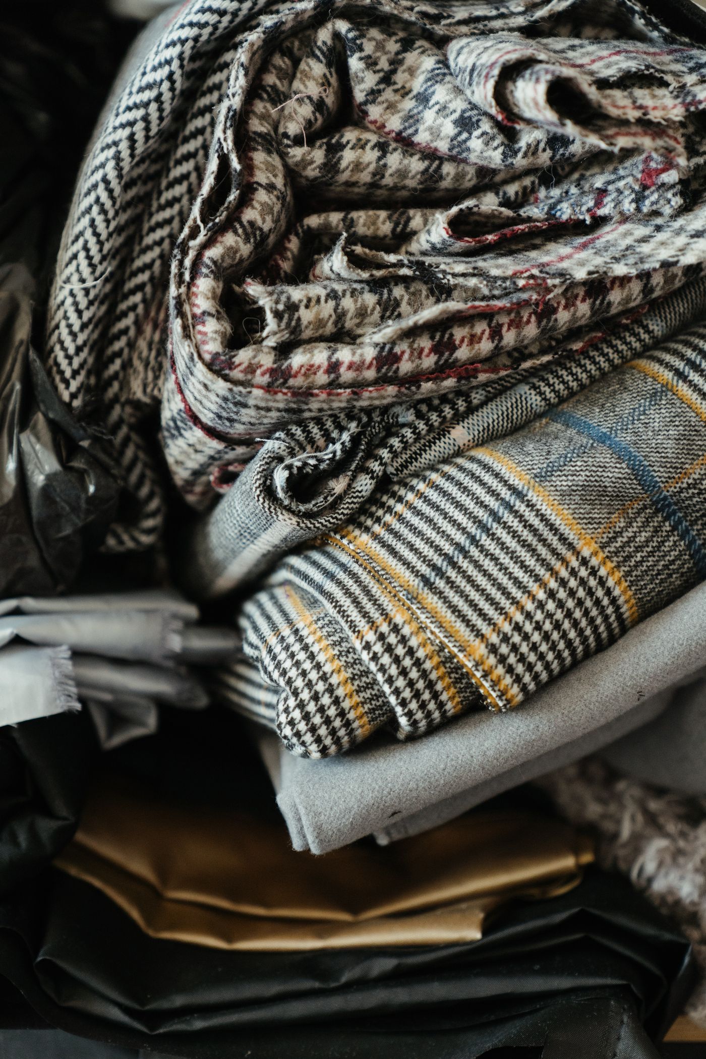 A stack of folded plaid, tweed and check designer fabrics