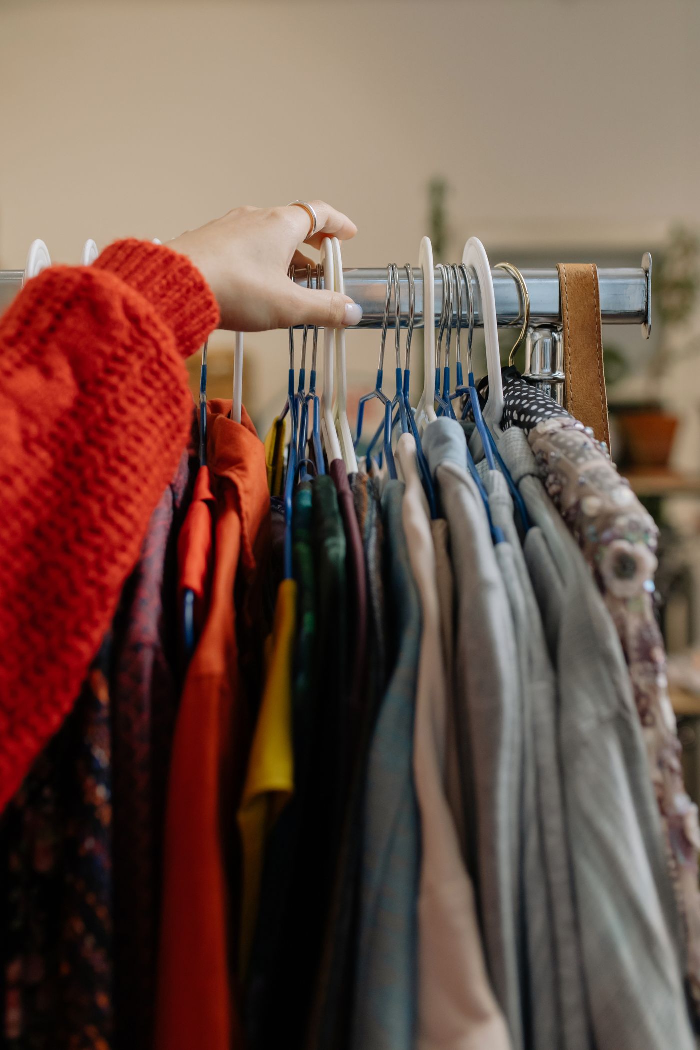 A hand reaching into a dense rack of designer fabrics