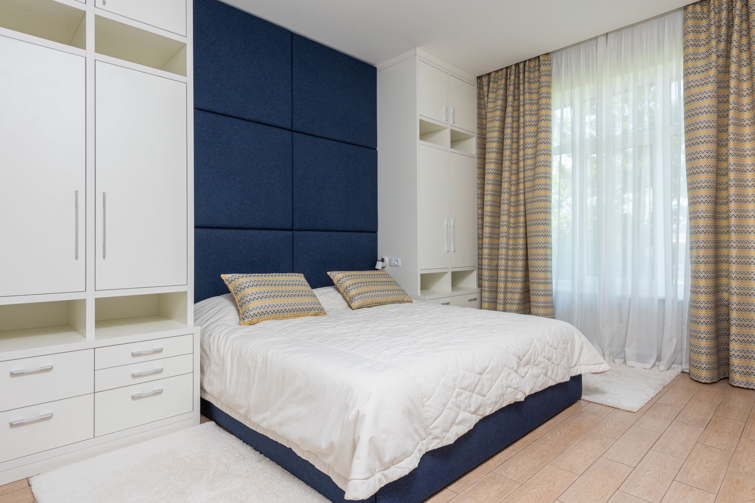 A freshly painted deep-navy feature wall in a bright bedroom
