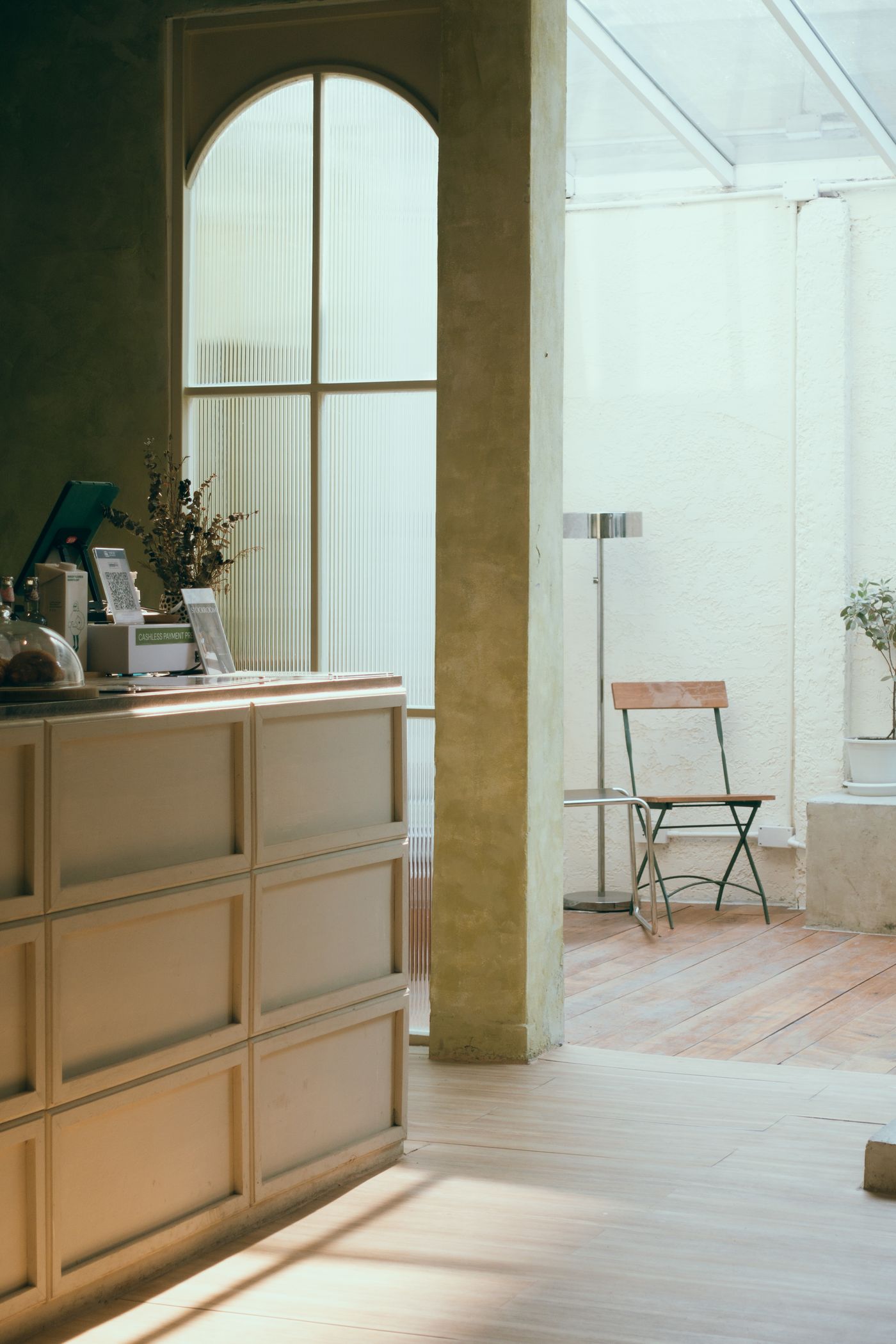 A calm, sunlit studio counter with an arched window and a plant