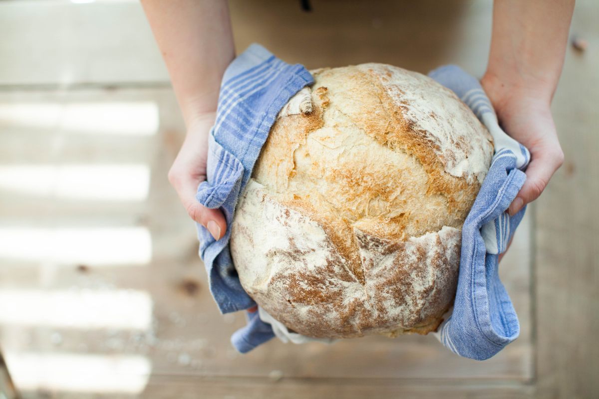 Hands holding a round artisan loaf in a striped cloth