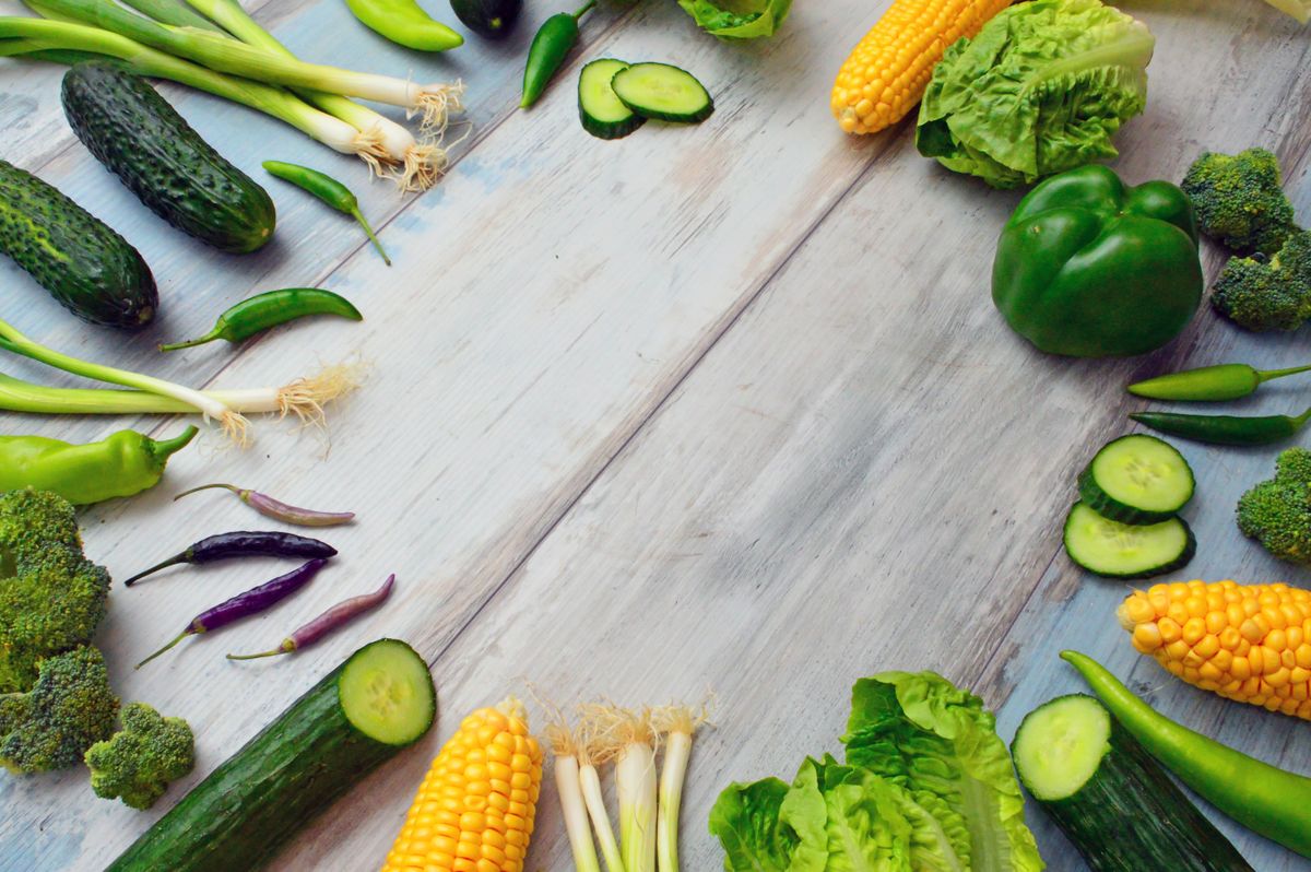 A border of fresh green vegetables on a wooden table