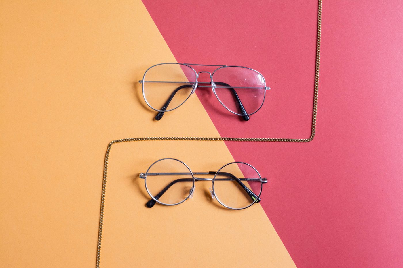 Two pairs of prescription frames on a bold colour-block background