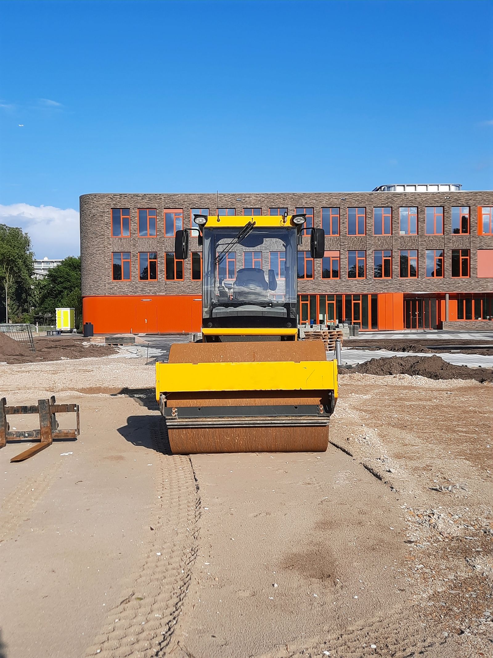 Yellow roller compacting a job site