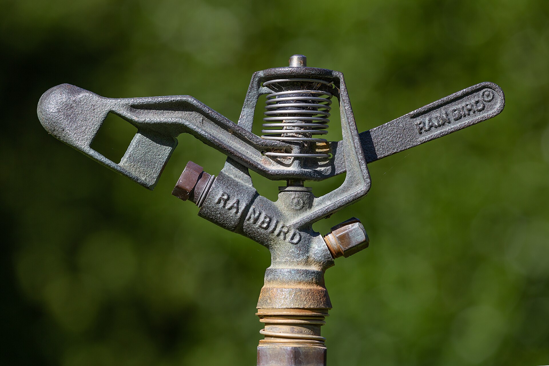 A close-up of an impact sprinkler head against green