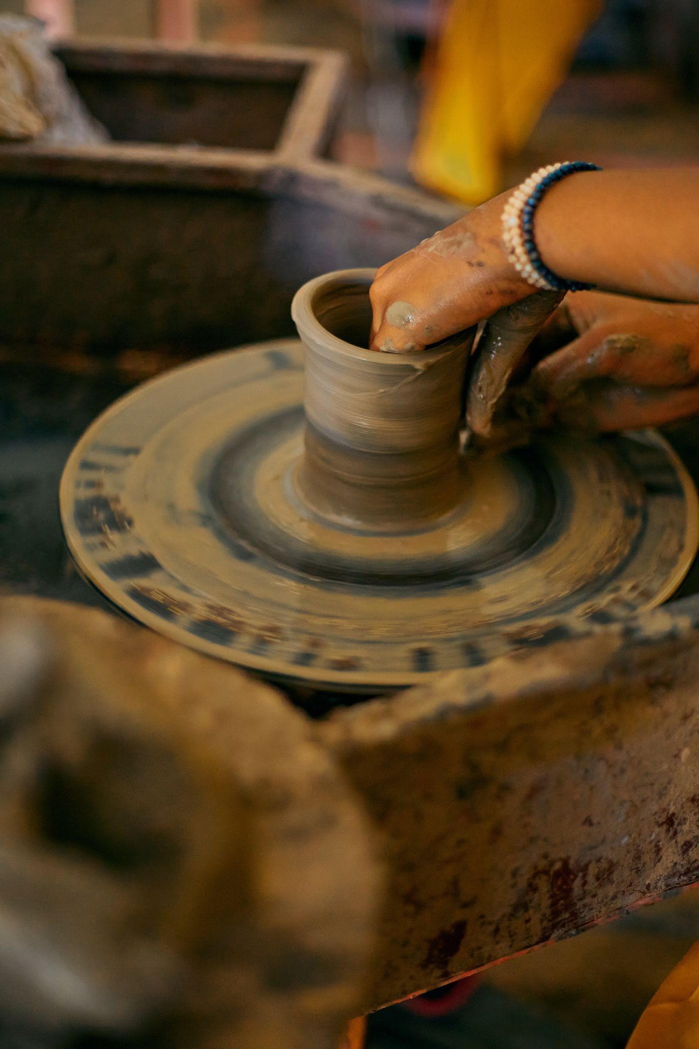 Hands shaping a clay bowl on a spinning pottery wheel