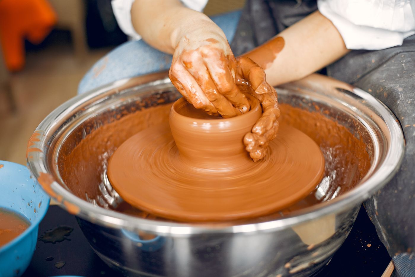 Hands throwing clay on a wheel