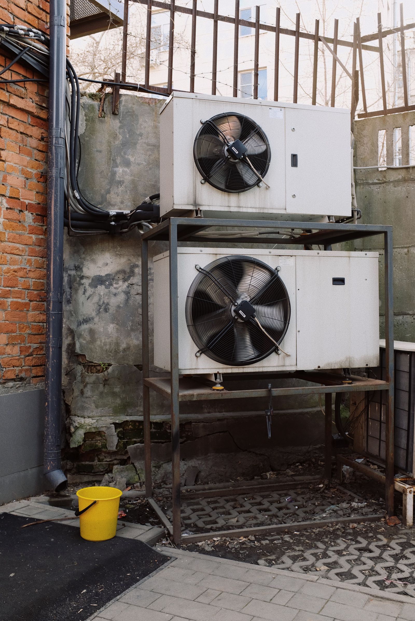 Two outdoor condenser units stacked on a steel stand