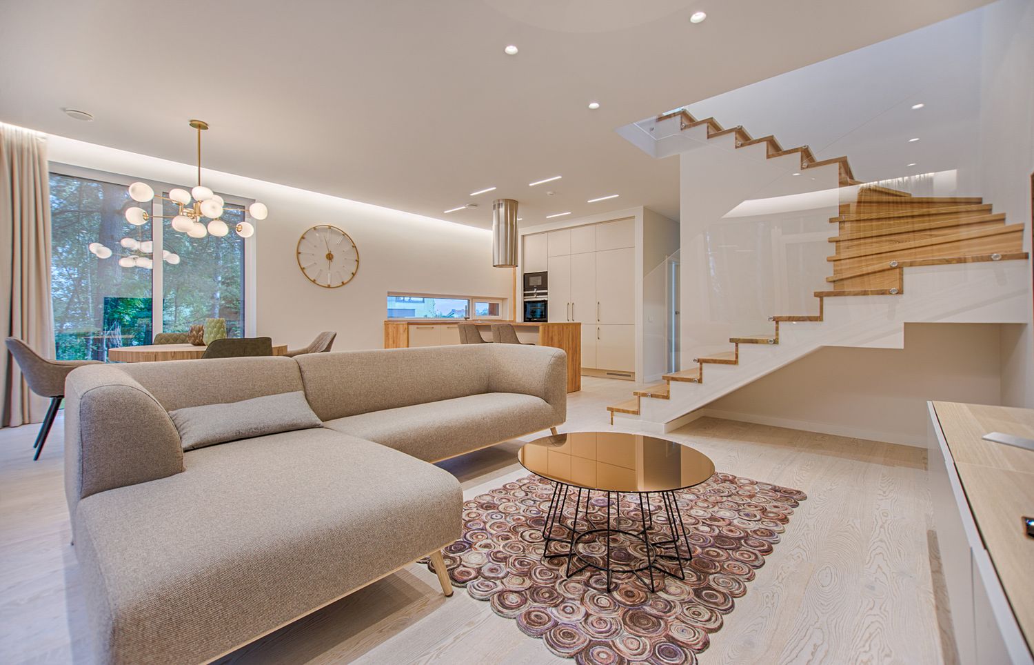 A renovated open-plan kitchen and living space with custom cabinetry and a feature staircase