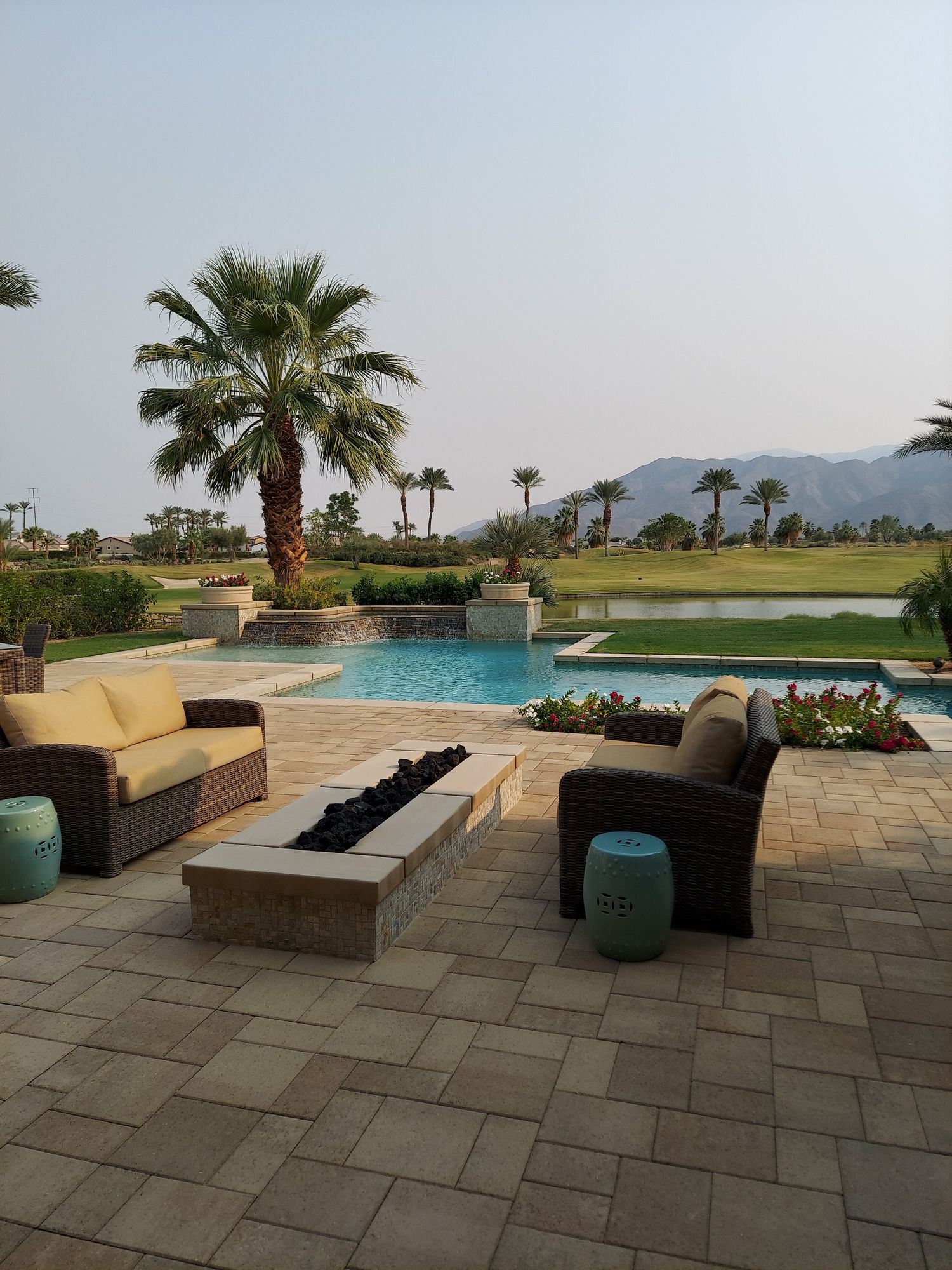 A poolside paved patio surrounded by greenery