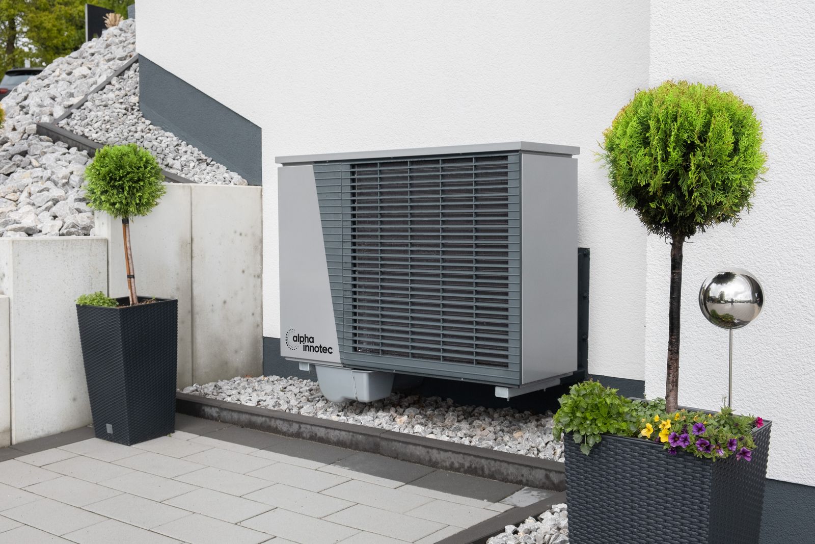 Modern outdoor heat-pump unit with planters beside a home
