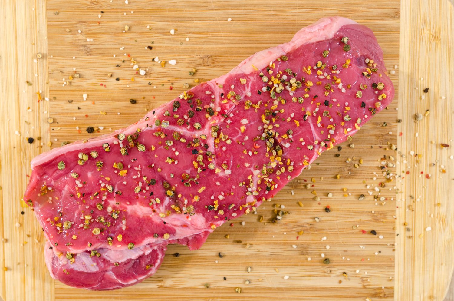 A whole striploin resting on a warm wooden butcher's block