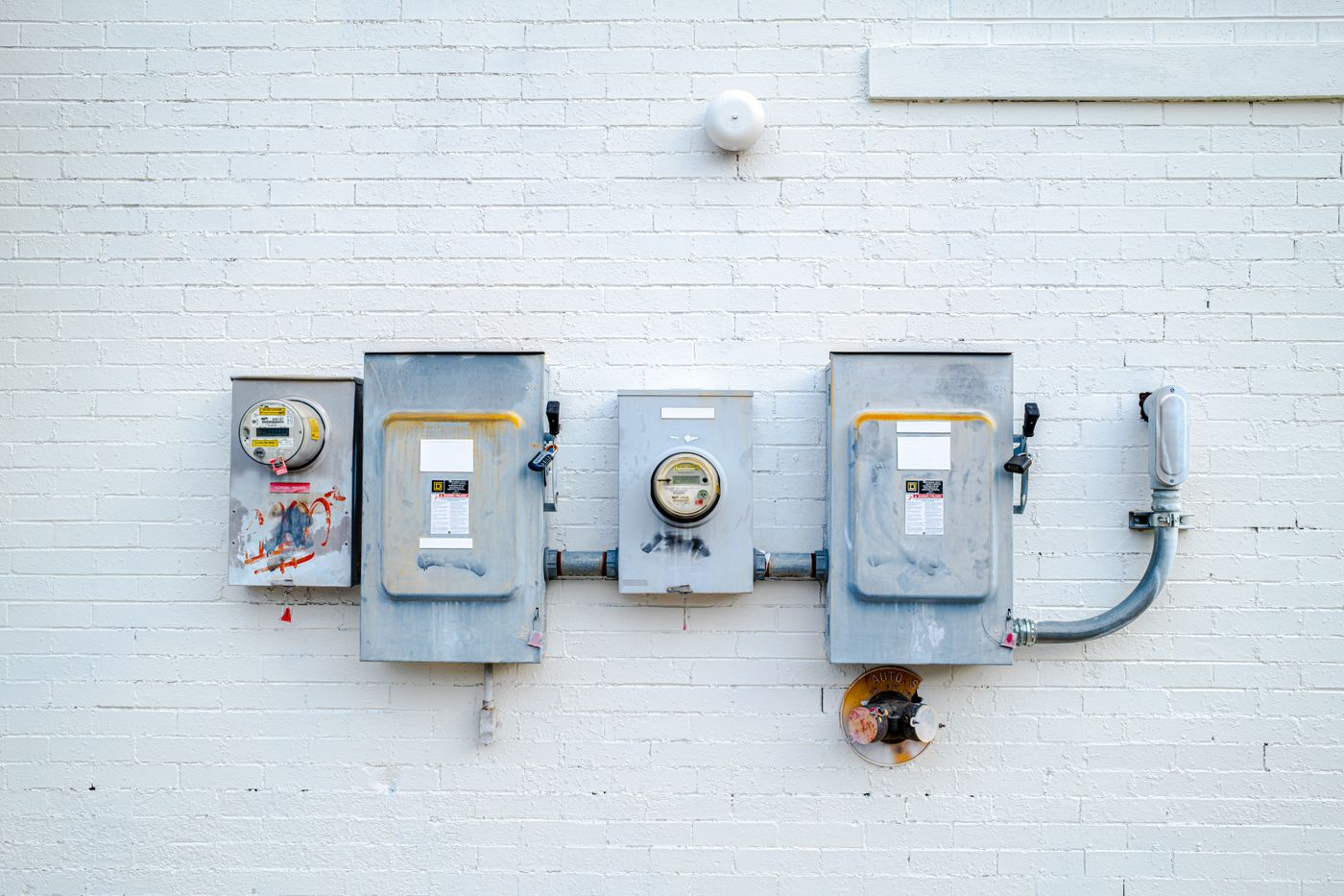 Electrical meters and boxes mounted on white brick