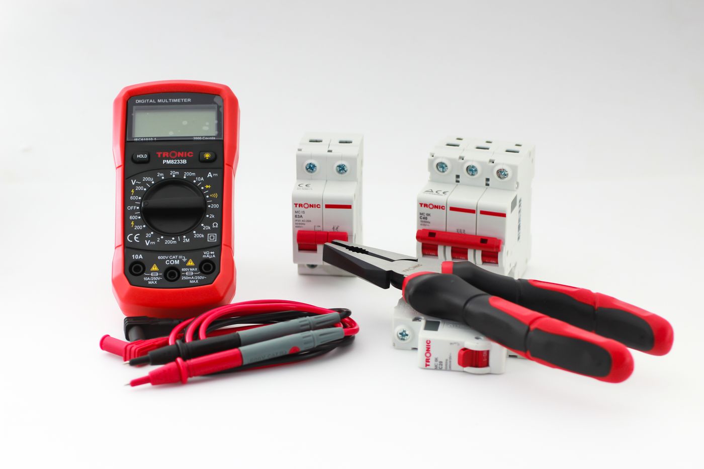A multimeter and hand tools laid out on a work surface