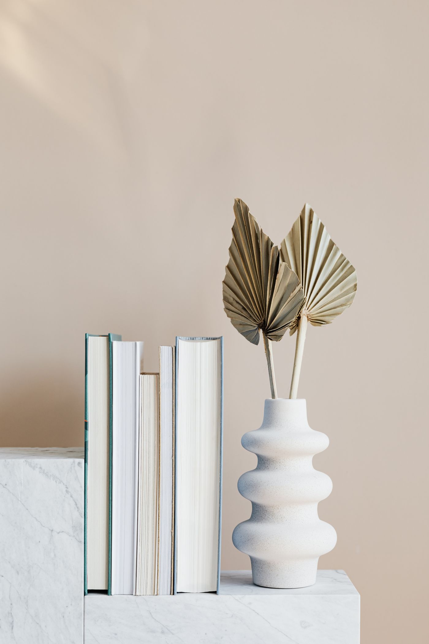A sculptural vase, books and dried palm styled together