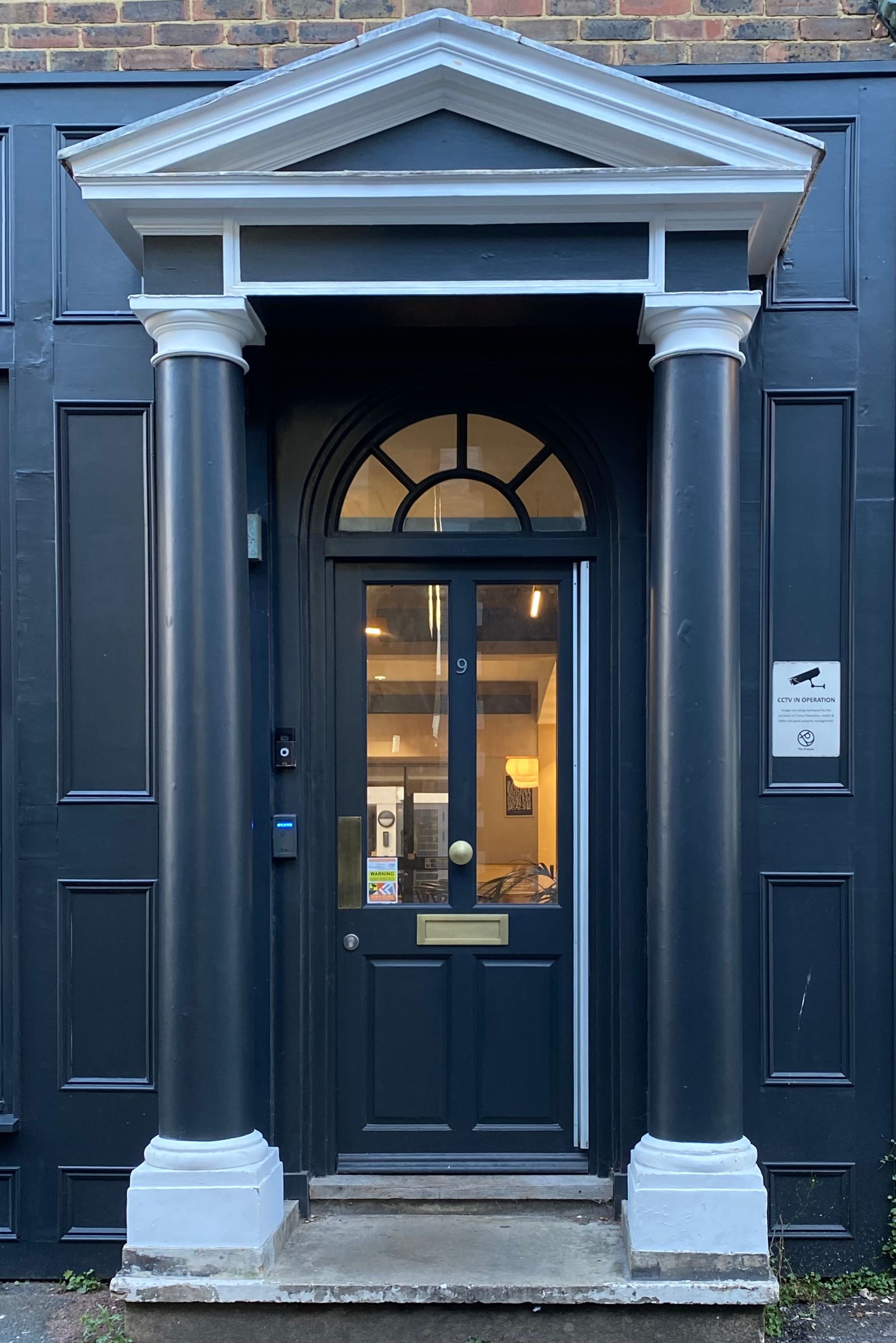 A navy entry door under a porch