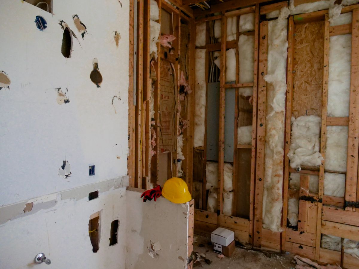 A wall stripped back to studs and insulation during water-damage repair