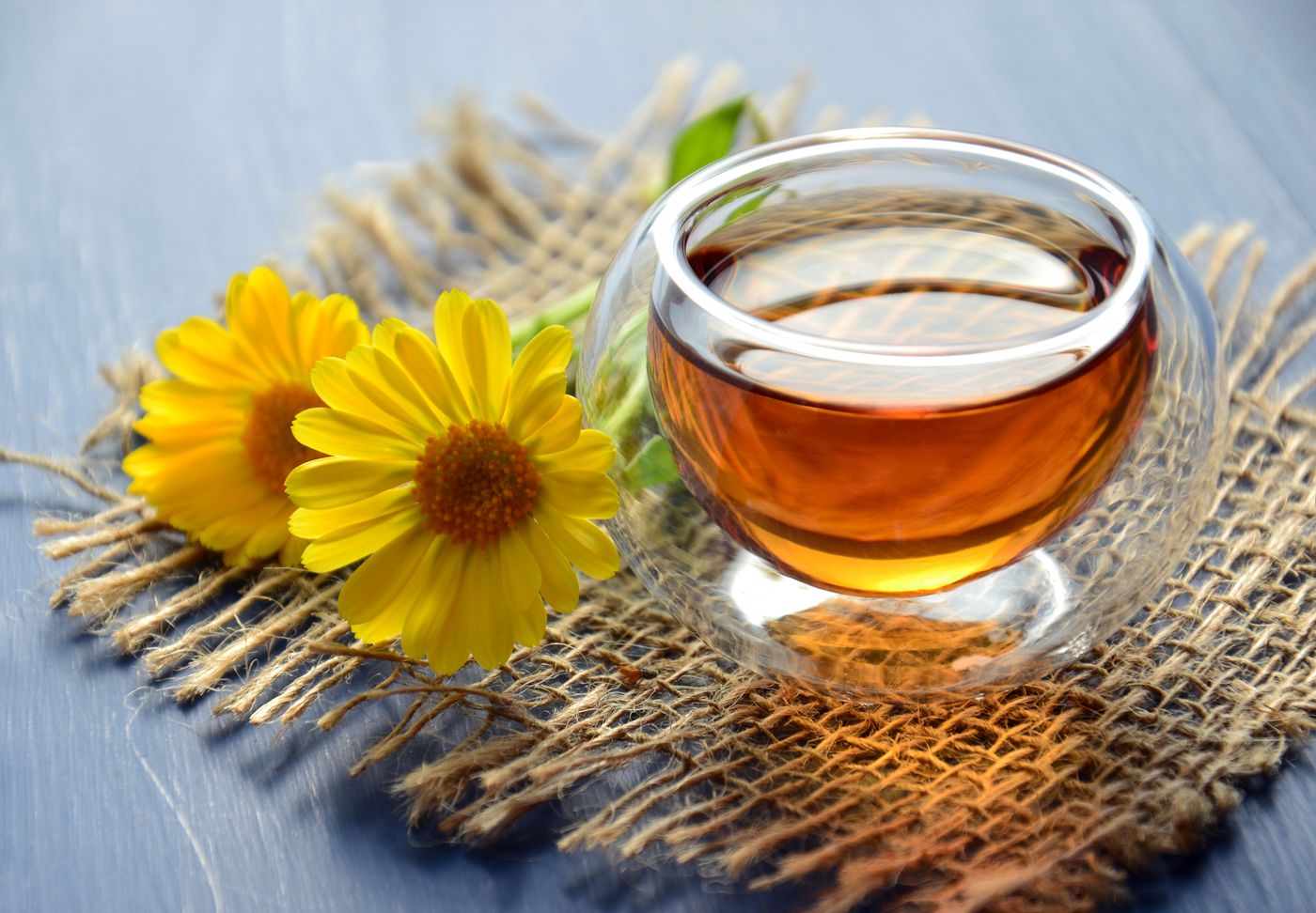 A honey dipper resting on burlap beside a single golden flower