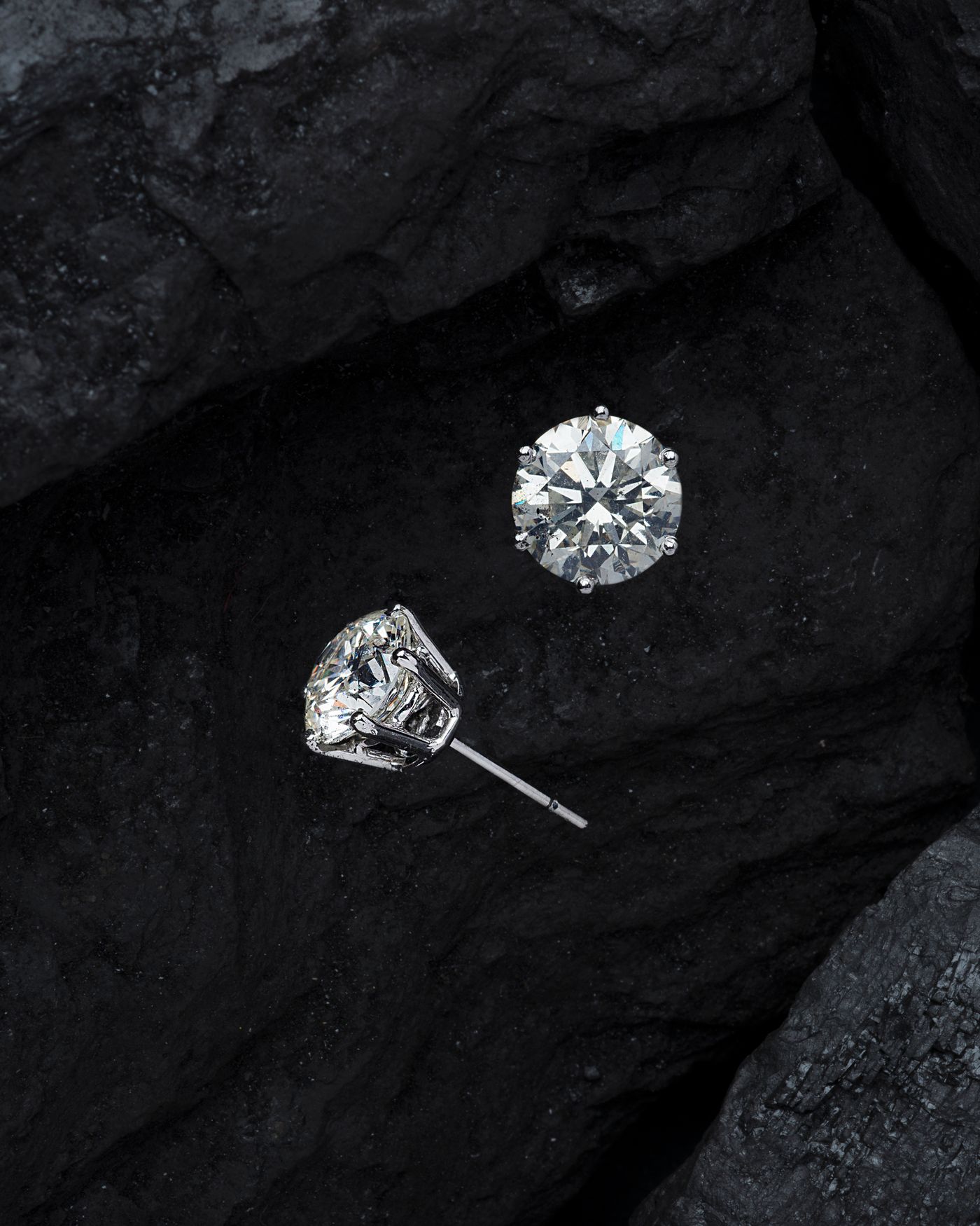 Two diamonds catching the light against a dark surface
