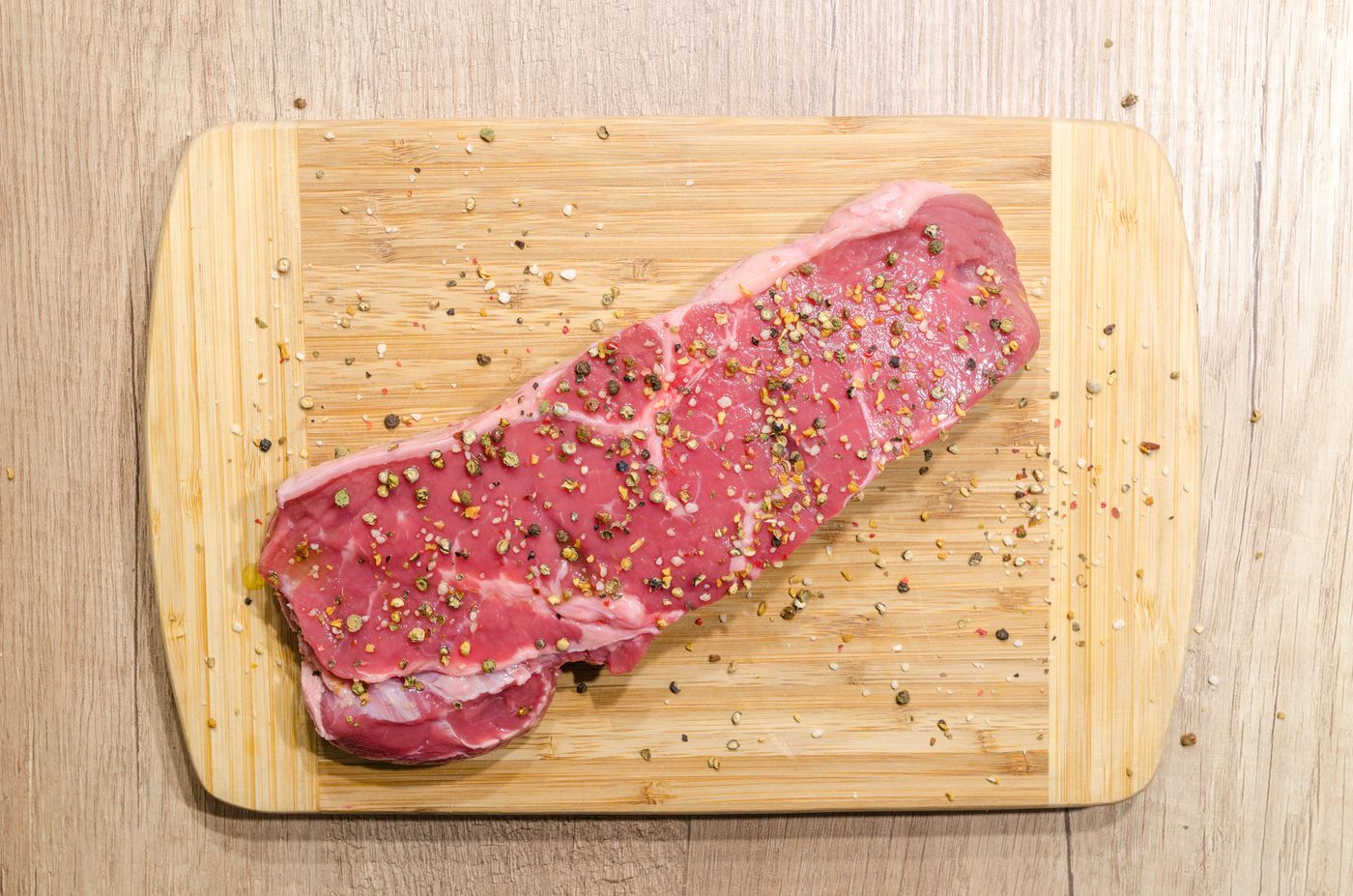 Raw steak on a wooden board with rosemary