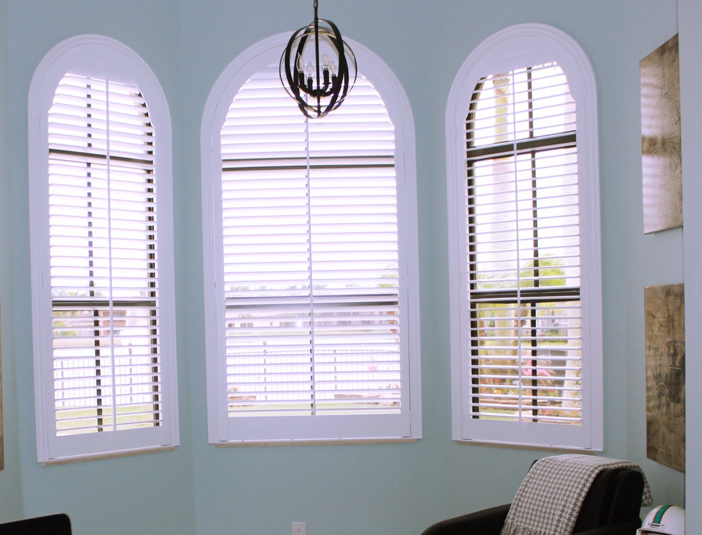 Plantation shutters fitted to arched windows in a bright room