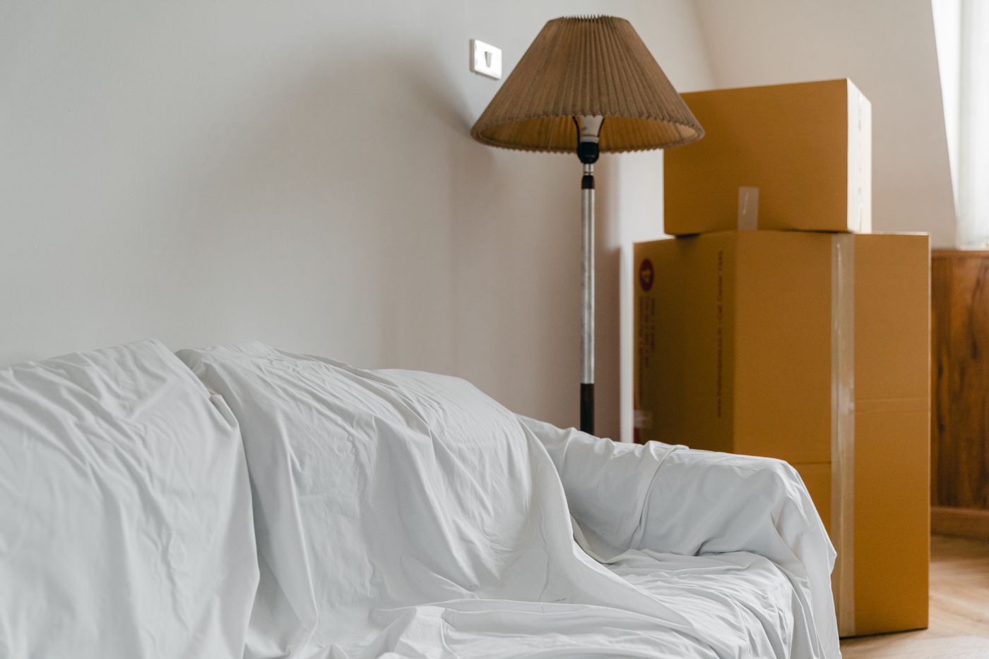 A sofa wrapped in a protective blanket beside packed boxes