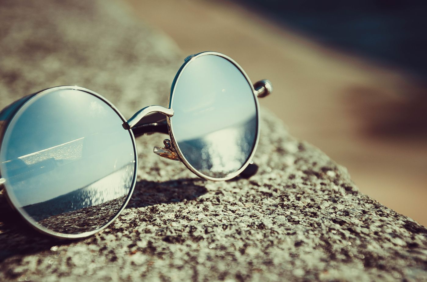 Mirrored round sunglasses resting on stone