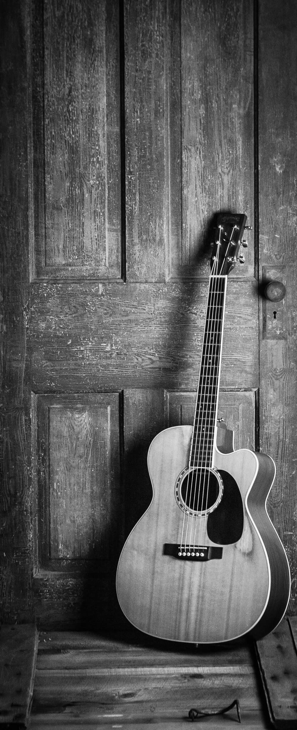 An acoustic guitar leaning against a wooden wall