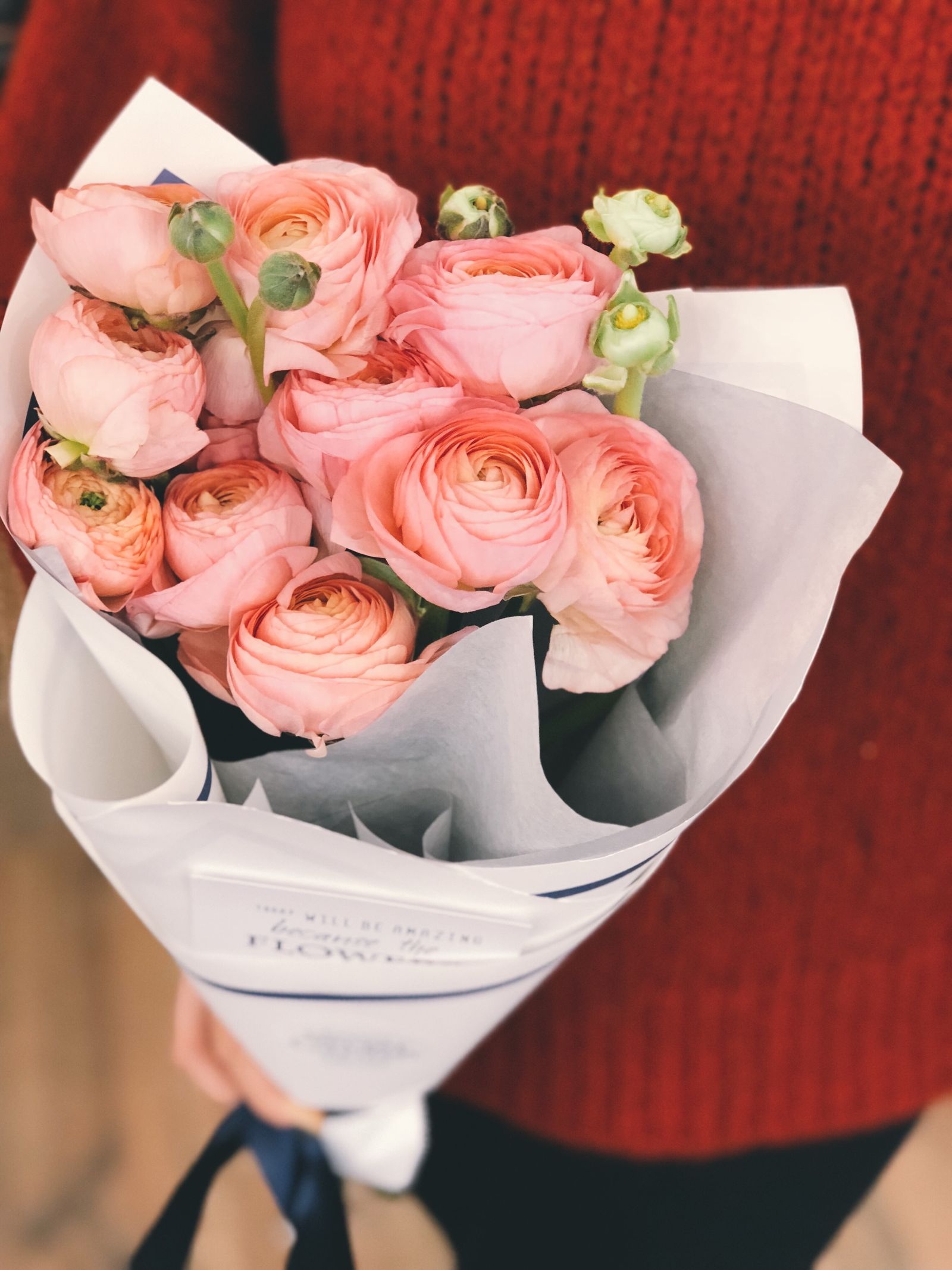 Hands holding a wrapped seasonal bouquet