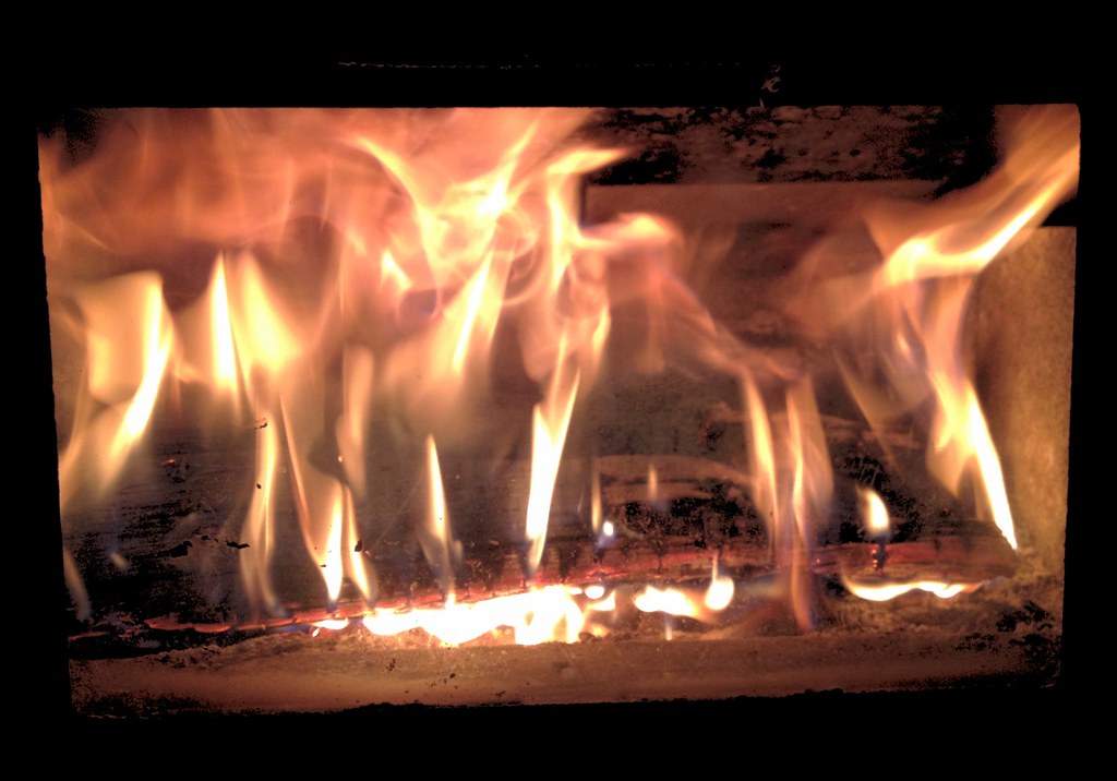 Flames over a fire bed behind glass