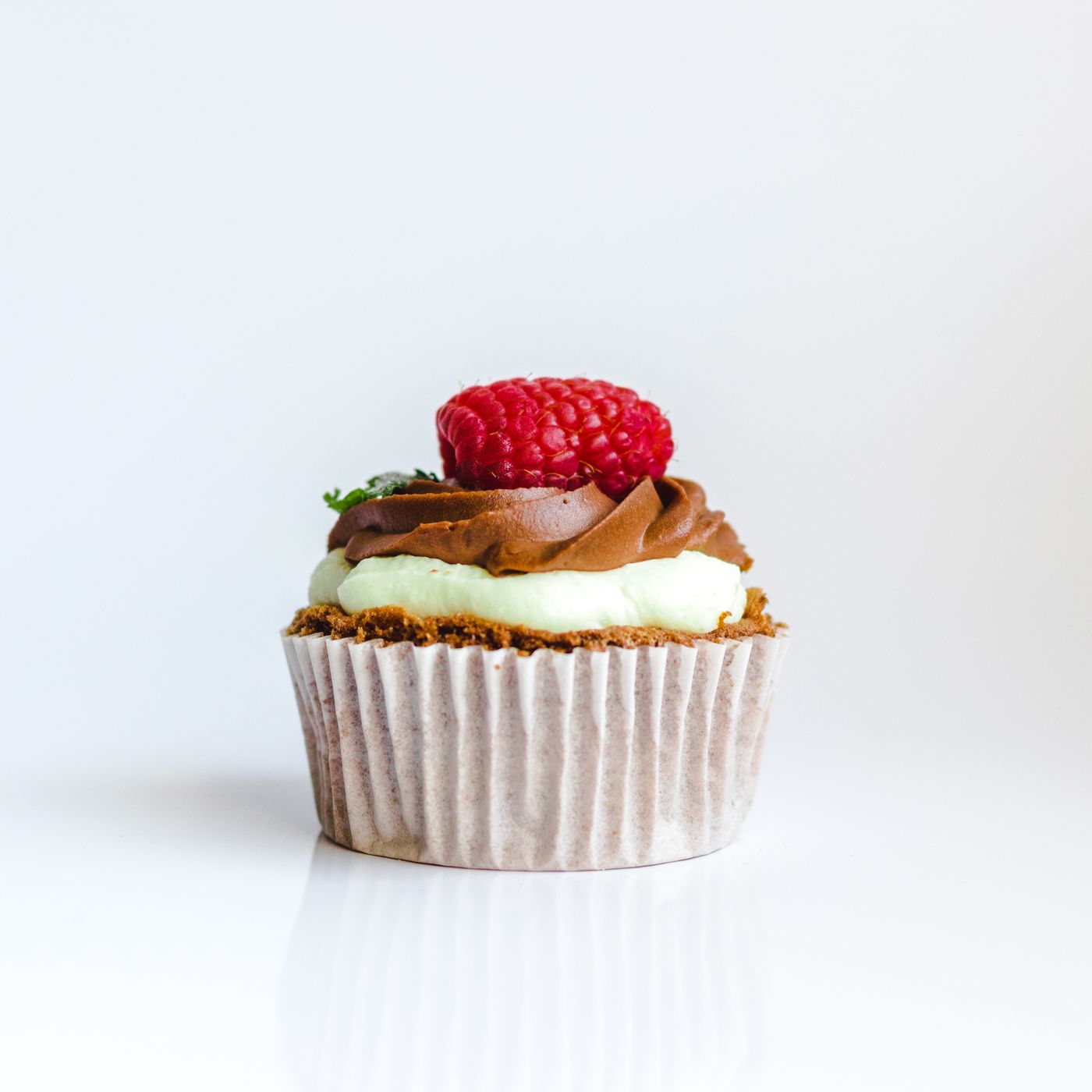A frosted cupcake topped with a raspberry