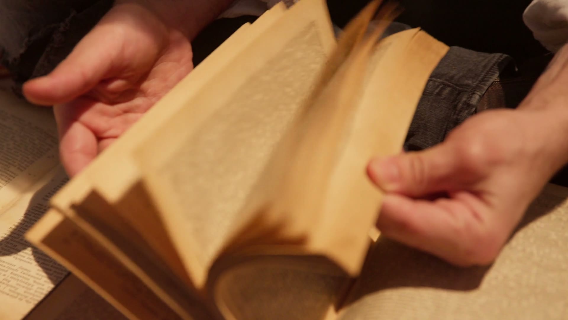 Hands turning the pages of an old book in warm light